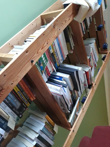 A shelf full of stacks of books, seen from below and at an angle