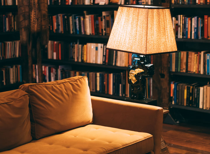 Photo of couch and reading lamp with bookcases in the background
